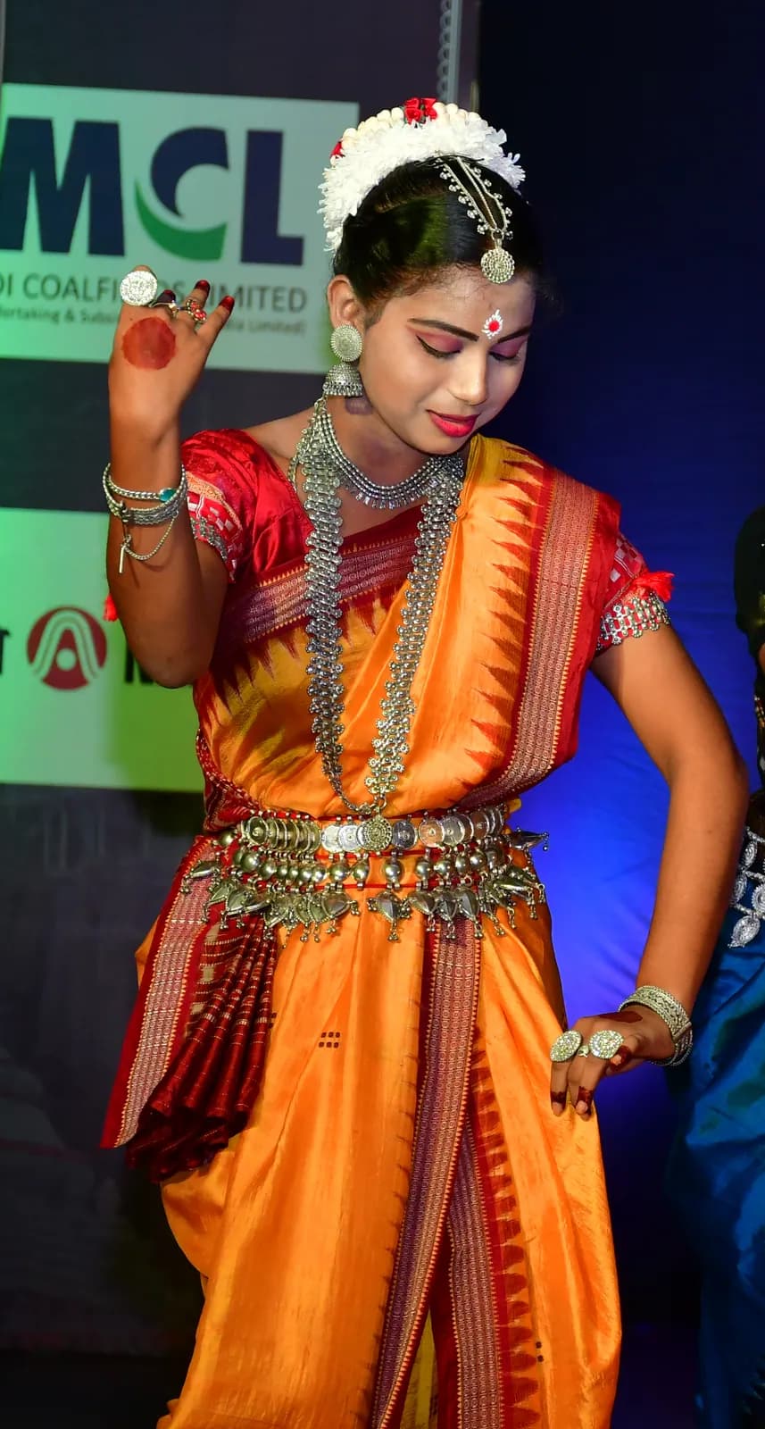 Two dancers in green, yellow and red costume holding a paired Odissi pose